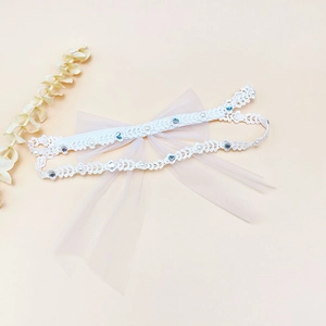 Détail du bandeau en dentelle blanche pour bébé avec grand nœud en tulle rose et perles
