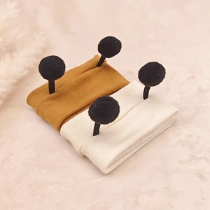 Detailed close-up of soft ribbed knit baby headbands with cute fuzzy antenna pom-poms