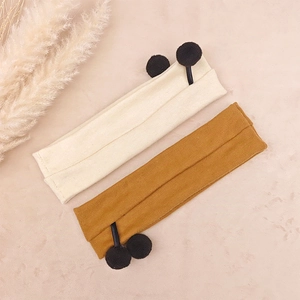 Detail of ribbed knit baby headbands in beige and yellow with cute black pom-poms