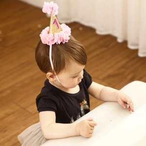Close-up of baby girl wearing gold sequin first birthday hat with pink number one