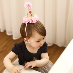 Pink and gold 1st birthday cone hat headband with tulle flowers on a baby girl