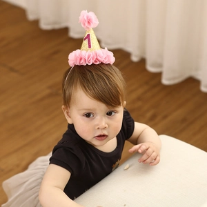 Detail of baby girl wearing gold glitter birthday crown headband with pink chiffon flowers