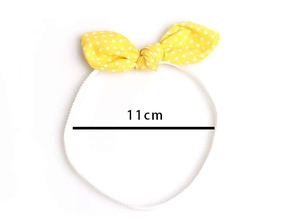 Detail showing 11cm yellow polka dot baby headband with elastic band on white background
