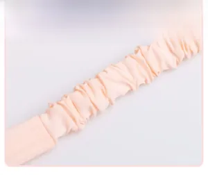 Close-up of soft light pink pleated silk fabric texture on an elastic baby headband