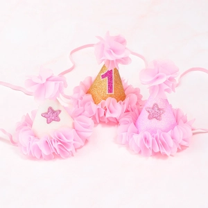 Close-up of three glittery 1st birthday party cone hats with tulle and gold star accents