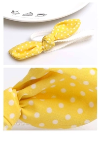 Detailed macro view of baby headband featuring yellow polka dot bow and white lace texture