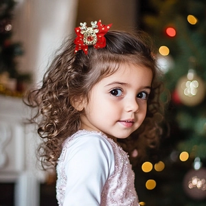 Dettaglio di una bambina con fiocco natalizio rosso con renna e pois dorati