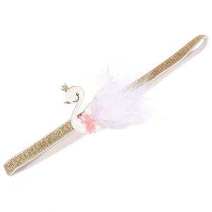 Detailed view of baby headband with golden glitter band, white swan and feather decor