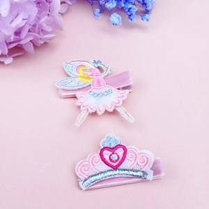 Détail de pinces à cheveux brodées fée de ballet et couronne de cœur pour enfants sur rose