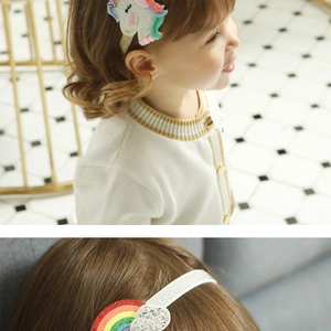 Close-up of glitter unicorn hair clip and rainbow headband detail for young girls