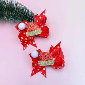 Dettaglio di fiocchi natalizi rossi a pois con cappello di Babbo Natale glitterato e pompon