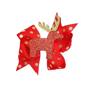 Dettaglio del fiocco per capelli rosso a pois dorati con motivo di renna glitterata