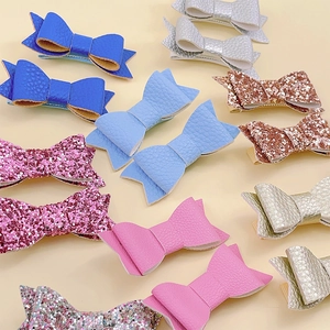 Detail of glitter and lychee grain leather bow hair clips in multiple bright colors