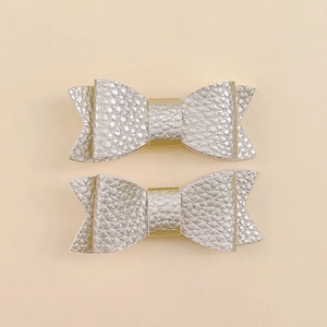 Close-up of champagne gold lychee leather hair clips with handmade bow design