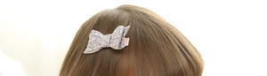 Close-up of pink glitter bow hair clip with textured leather and sparkling sequins