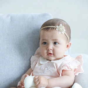 Close-up of baby girl wearing floral nylon headband with embroidery detail