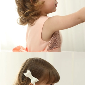 Detail of pink-orange sequins on a girl dress with matching floral bow hair clip