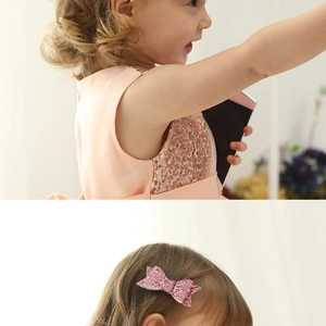Detail of pink glitter hair clip and sequin dress worn by a young girl in soft lighting
