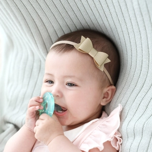 Close-up of a baby wearing a gold PU leather bow headband with soft elastic strap