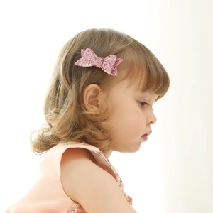 Close-up of a pink glitter bow hair clip worn by a girl for festive hairstyling