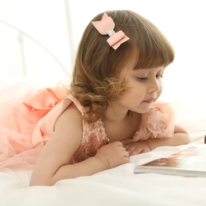 Pink lychee leather hair bow clip worn by a toddler in a shiny sequin dress details
