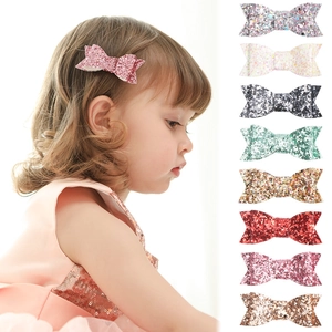 Detail view of multi-color glitter bow hair clips and child model wearing pink bow accessory