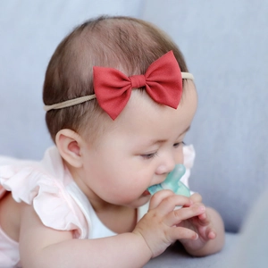 Close-up of a baby wearing a red cotton linen bow headband with soft nylon strap