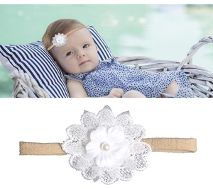 Détail d'un bandeau bébé avec fleur en dentelle blanche, pétales en tissu et perle