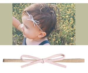 Dettaglio fascia per neonata con fiocco rosa in camoscio e fascia in nylon ad alta elasticità