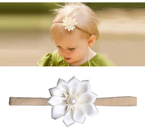 Détail d'un bandeau bébé avec fleur en tissu blanc et perle sur bande beige souple