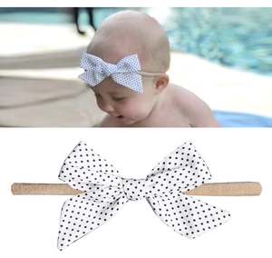 Détail du bandeau bébé avec nœud blanc à pois noirs et élastique en nylon souple