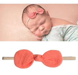 Dettaglio del fiocco in cotone rosa corallo su fascia elastica in nylon per neonati