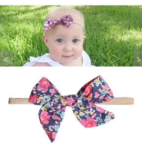 Detailaufnahme Baby-Haarband aus Nylon mit lila Blumenschleife auf grünem Gras