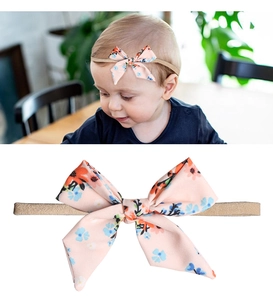 Detail of floral infant headband showing high-elastic band and orange chiffon bow