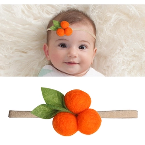 Detailansicht eines Baby-Stirnbandes mit orangefarbenen Pompons und Filzblättern