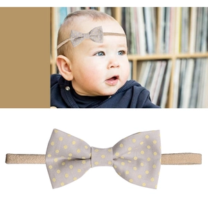 Detail of baby headband featuring grey fabric bow with bright yellow polka dots