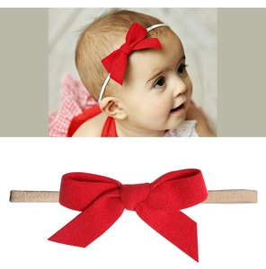 Detail showing red oversized bow baby headband with soft texture and elastic band