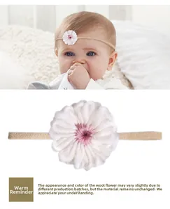 Detail eines Baby-Stirnbands mit handgefertigter weißer Häkelblume und elastischem Band