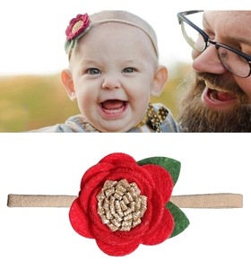 Detail of red felt flower baby headband with gold glitter core and soft elastic band