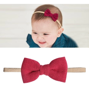 Detail of red linen bow on elastic beige headband for infants showing soft fabric texture