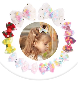 Detail view of mesh bow hair clips with colorful plush balls and resin unicorns
