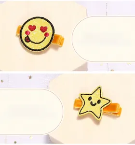 Detalle de horquillas bordadas amarillas con cara sonriente y estrella en tela suave
