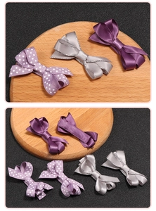 Detail of handmade bow hair clips in purple and silver with polka dots on a wooden tray