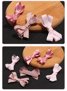 Detailed close-up of pink grosgrain bow hair clips with polka dots and satin texture
