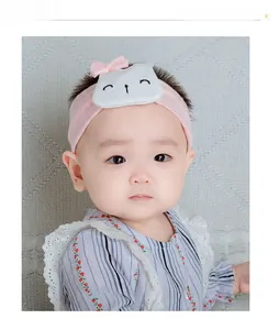 Detailed view of pink elastic cotton baby headband with cartoon cat patch and pearl bow