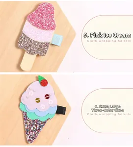 Dettaglio di fermagli per capelli glitterati con disegni di ghiaccioli rosa e cono gelato