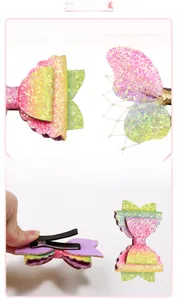 Detailed close-up showing gradient glitter fabric and metal alligator clip of the butterfly hair pin