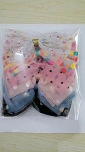 Close-up of mesh bow hair clips with colorful polka dots and star sequins in packaging