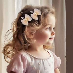 Close-up of sweet beige mesh bow hair clips with gold stars on a little girl