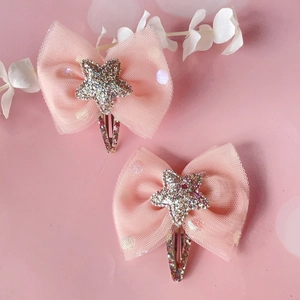 Close-up of pink polka dot mesh hair clips with glitter star and gold bow detail
